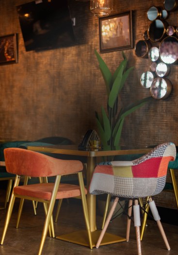 A table for two at ÉKO '77 Wolverhampton against a copper wall, under a cluster of round mirrors