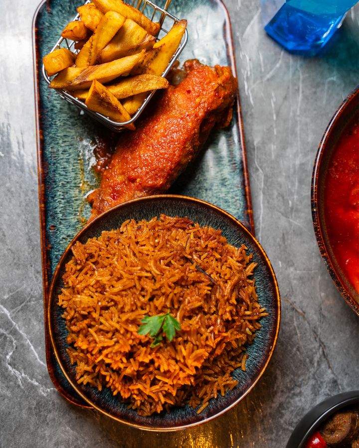 Jollof rice with grilled fish and a basket of chips