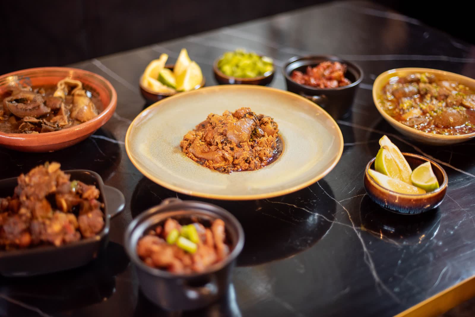 A plate of rice at the centre of a table of small terracotta and black bowls