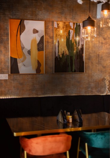Two framed abstract prints above the banquette at ÉKO '77 Pershore Road, with pendant lamps over a marbled table