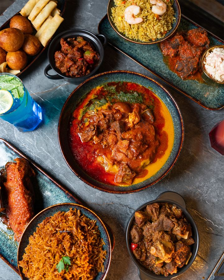 A full table — jollof rice, stew, peppered meat and sides put down together