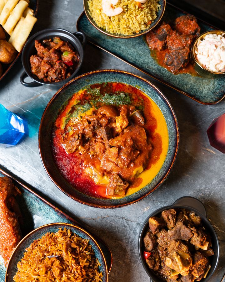 Stew, jollof and peppered meat laid across a marble table